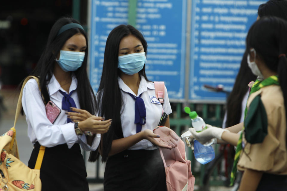 Students disinfect their hands to avoid the contact of coronavirus before their morning class at Santhormok high school, in Phnom Penh, Cambodia, Monday, Nov. 2, 2020. Schools throughout Cambodia that had been shut in March because of the coronavirus crisis reopened Monday, but with limits on class sizes and hours. (AP Photo/Heng Sinith)