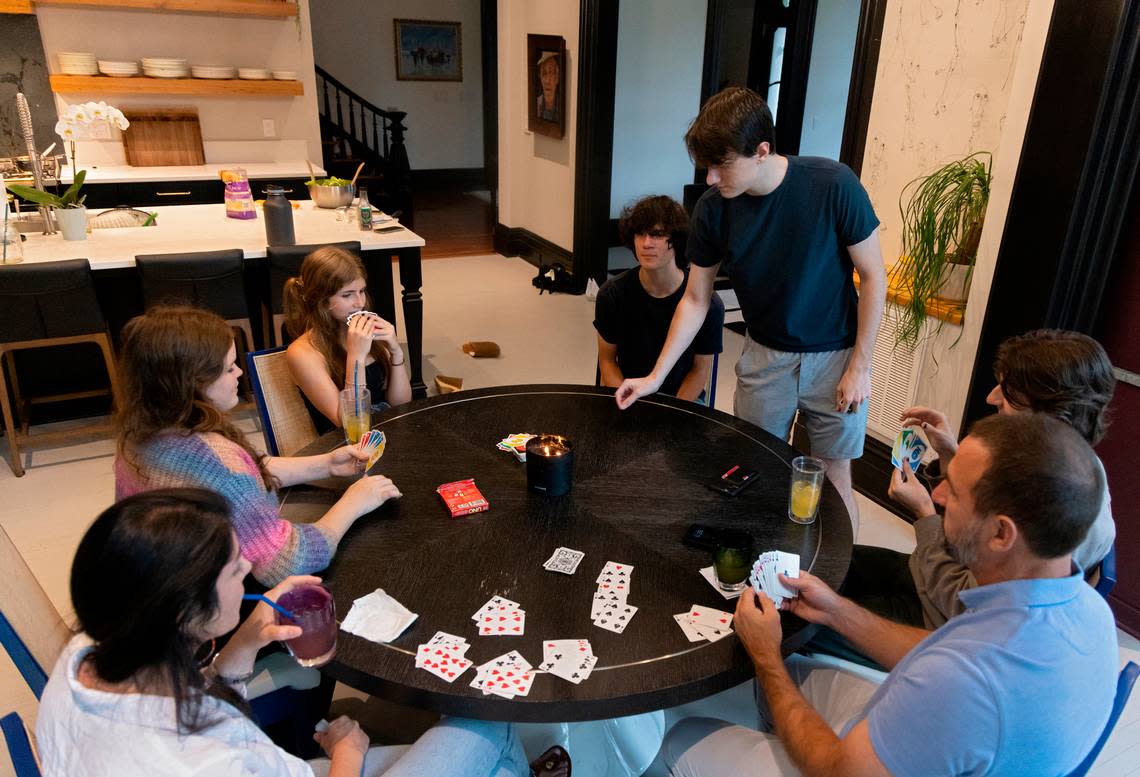 Tina Konidaris and Jeff Turpin play cards with their children, from left, Melina Kuehn, 16, Talia Kuehn, 13, Asher Turpin, 16, Andrew Turpin, 19, and Alexander Turpin, 17, as dinner cooks at the Andrews-Duncan House on May 25, 2023, in Raleigh. The family moved into the nineteenth-century house in February after spending about five years renovating it.