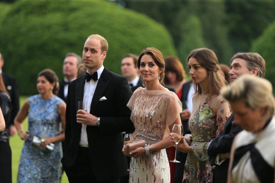 Prince William, Kate Middleton, and Rose Hanbury with a crowd of other people in a garden.