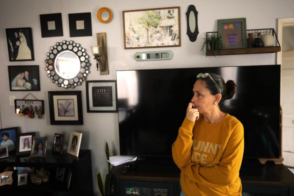 Claudia Aleman in the living room of her family home with photos on the wall.