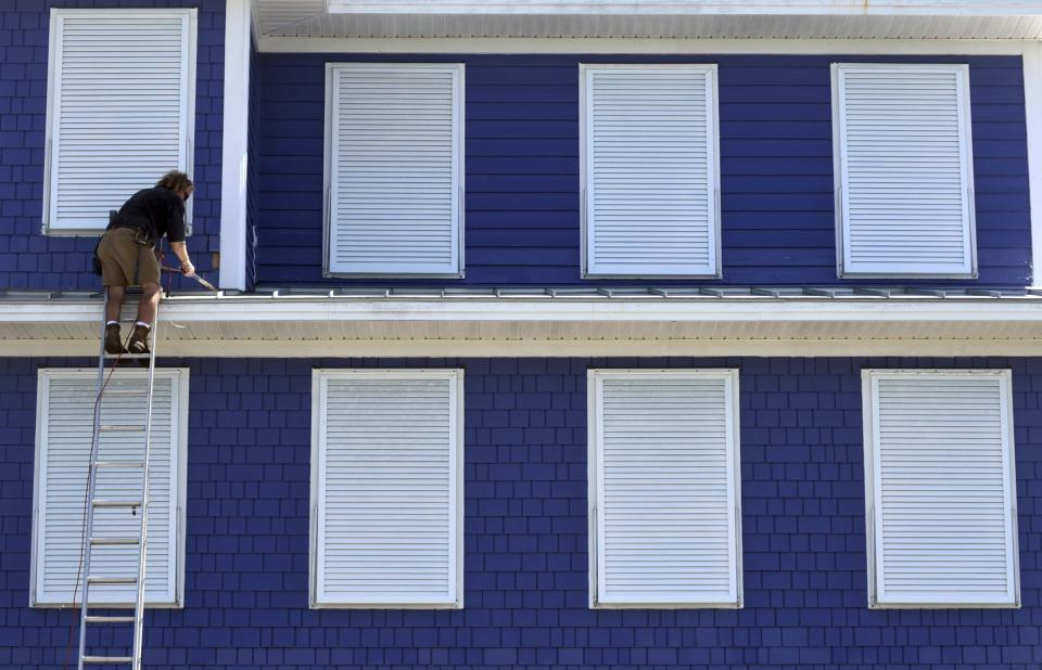 Marion Eason finishes up putting the hurricane shutters on a house in Kure Beach N.C., , Tuesday, Sept. 3, 2019, as residents make preparations for Hurricane Dorian. (Matt Born/The Star-News via AP)