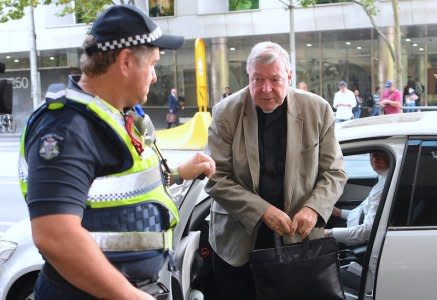 FILE PHOTO: Vatican treasurer Cardinal George Pell is assisted by an Australian policeman as he gets out of a car upon arriving at the Melbourne Magistrates' Court in Australia, March 15, 2018. AAP/Joe Castro/via REUTERS