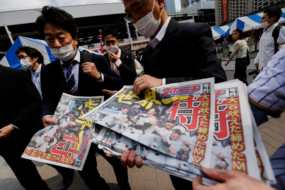 日本隊22日在世界棒球經典賽擊敗美國隊奪隊史第3冠，多家報社等在街頭贈送號外，東京民眾搶拿。（路透）