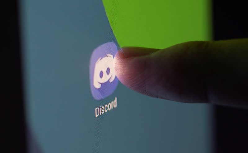 Woman touches Discord app on smartphone in this illustration taken