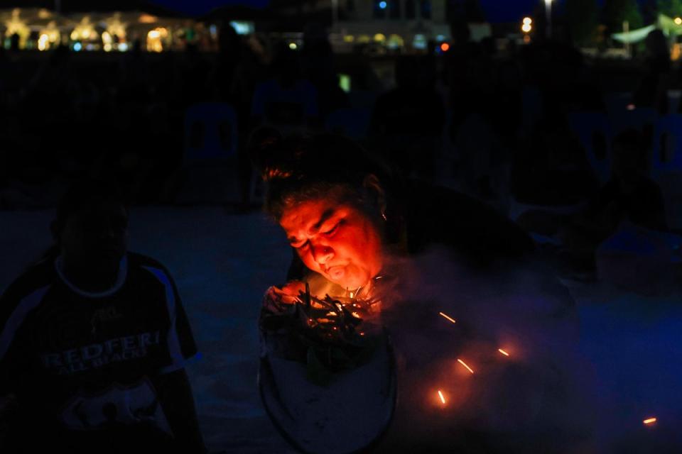 Rowena Welsh-Jarrett blows on native plants to produce smoke at Bondi Beach for a Dawn Reflection and Smoking Ceremony on 26 January, 2024 (Getty Images)