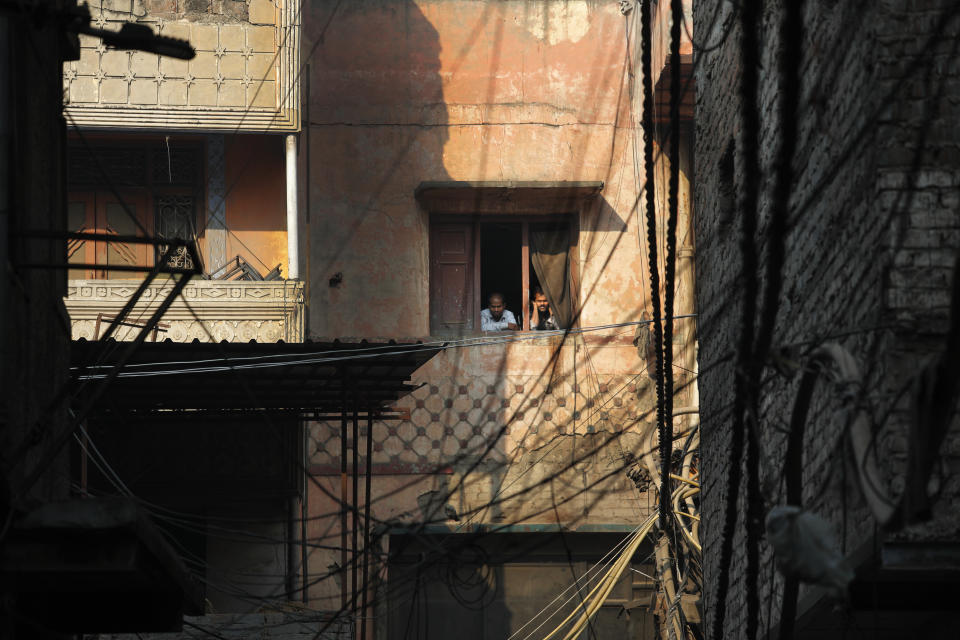 People living near a building which caught fire on Sunday look out from a window in New Delhi, India, Monday, Dec. 9, 2019. Authorities say an electrical short circuit appears to have caused a devastating fire that killed dozens of people in a crowded market area in central New Delhi. Firefighters fought the blaze from 100 yards away because it broke out in one of the area's many alleyways, tangled in electrical wire and too narrow for vehicles to access. (AP Photo/Manish Swarup)