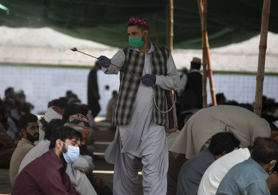 A volunteer sprays disinfectant on worshippers gather to offer Friday prayers in Rawalpindi, Pakistan, June 12, 2020. Pakistan ranks among countries hardest hit by the coronavirus with infections soaring beyond 18,000, while the government, which has opened up the country hoping to salvage a near collapsed economy, warns a stunning 1.2 million Pakistanis could be infected by the end of August. (AP Photo/B.K. Bangash)