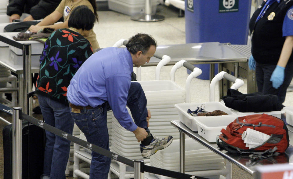 FILE - In this Monday, Jan. 4, 2010, file photo, an airline passenger pulls off his shoes to be scanned as he prepares to go through a security checkpoint at Seattle-Tacoma International Airport, Monday, Jan. 4, 2010, in SeaTac, Wash. The U.S Department of Homeland Security said Wednesday, Feb. 19, 2014, it is warning airlines that terrorists could try to hide explosives in shoes. It's the second time in less than three weeks that the government has issued a warning about possible attempts to smuggle explosives on a commercial jetliner. (AP Photo/Elaine Thompson, File)