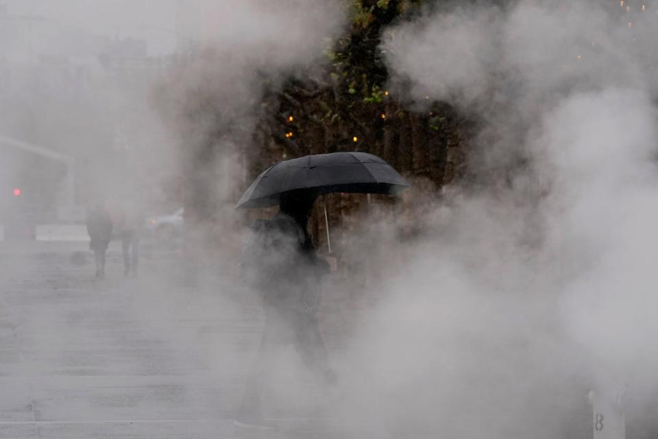 A pedestrian carries an umbrella while walking at Civic Center Plaza in San Francisco (Copyright 2022 The Associated Press. All rights reserved)