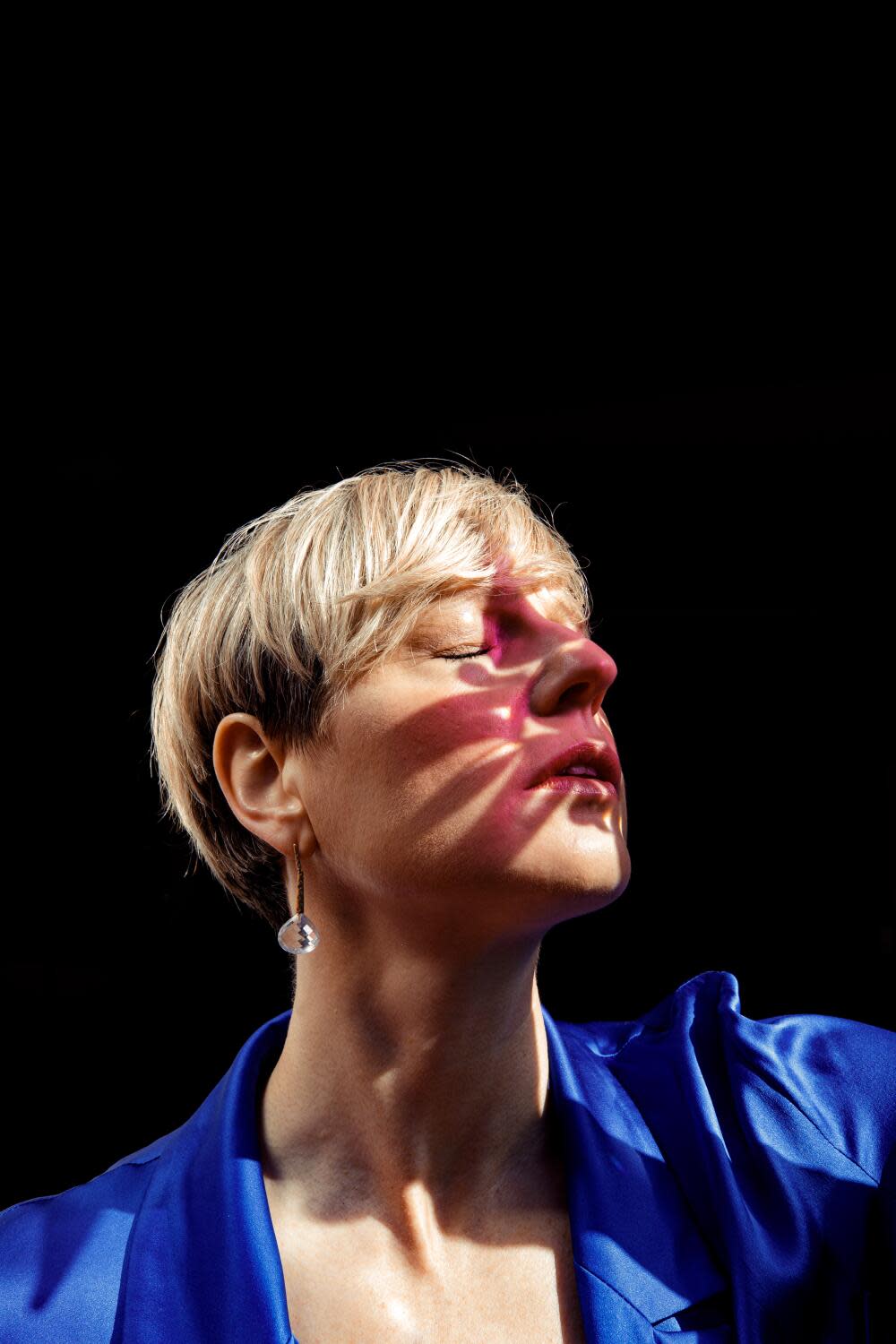 A woman poses with shadows across her face.