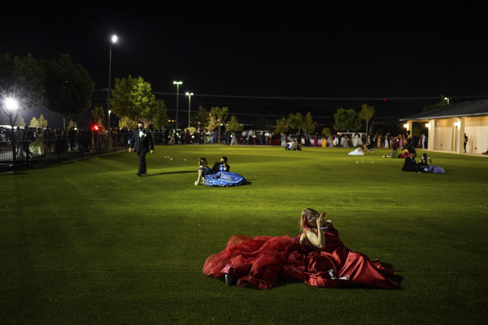 Julie Lattang, 18, and Brianna Cazadillas, 17, laugh with each other on a field while attending prom at the Grace Gardens Event Center in El Paso, Texas on Friday, May 7, 2021. Around 2,000 attended the outdoor event at the private venue after local school districts announced they would not host proms this year. Tickets cost $45. (AP Photo/Paul Ratje)