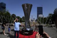 A man poses for a photo next to a replica of the Europa Conference League trophy ahead of the final between Roma and Feyenoord in Tirana, Albania, Wednesday, May 25, 2022. (AP Photo/Thanassis Stavrakis)