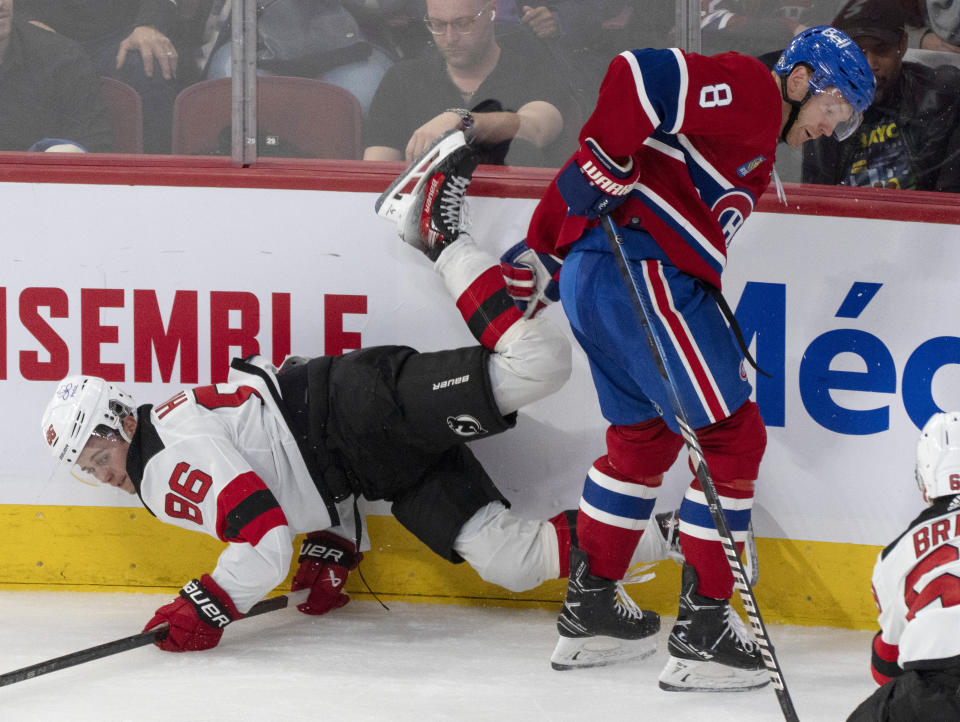 New Jersey Devils' Jack Hughes (86) is checked into the boards by Montreal Canadiens' Mike Matheson (8) during the second period of an NHL hockey game Tuesday, Oct. 24. 2023, in Montreal. (Christinne Muschi/The Canadian Press via AP)