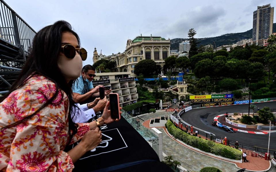 Spectators watch from a rooftop as Alpine's Spanish driver Fernando Alonso drives during the third practice session at the Monaco street circuit ahead of the Monaco Formula 1 Grand Prix - ANDREJ ISAKOVIC / AFP