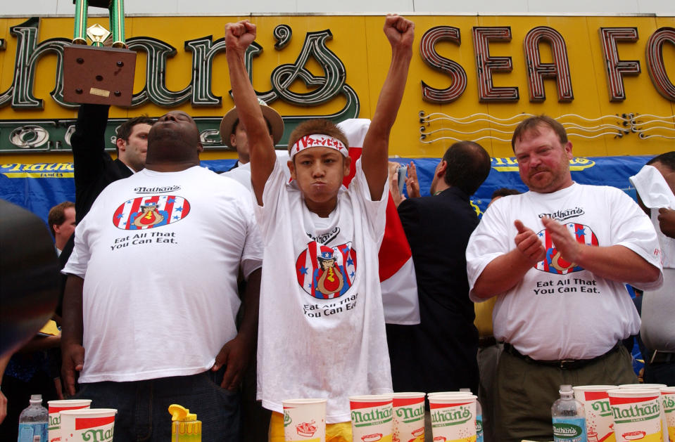 Contestants applaud as 23-year-old Takeru Kobayash raises his hands in victory July 4, 2001 at the 86th annual Nathan's Hot Dog Eating Contest at Coney Island in Brooklyn, New York.