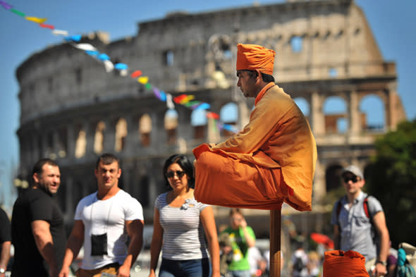 ROME, ITALY - MAY 14:  A street performer gets second glances as he appears to sit solely on a pole near the Colosseum on Tuesday May 14, 2013 in Rome, Italy.  (Photo by Matt McClain/ The Washington Post)