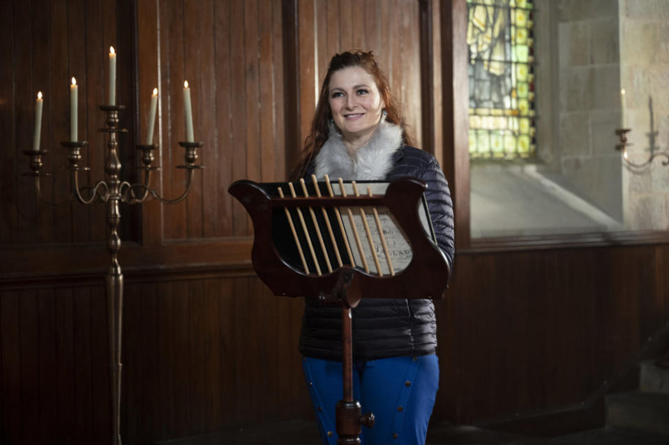 Rachel stands behind a music stand