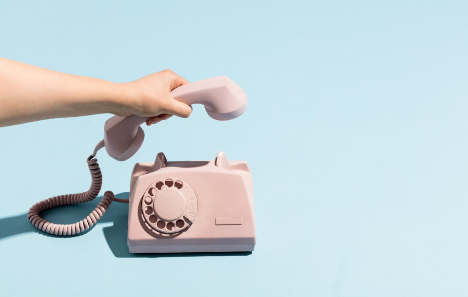 Woman's hand putting a retro telephone reciever down, hanging up