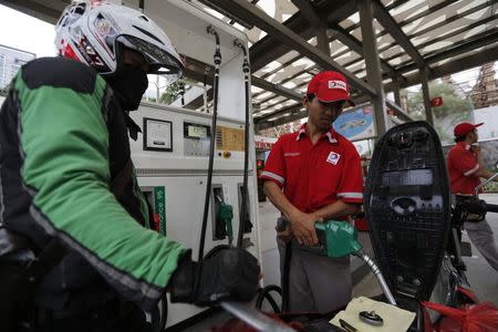 An employee at a Total fuel station fills up a motorcycle in south Jakarta February 12, 2015. REUTERS/Darren Whiteside