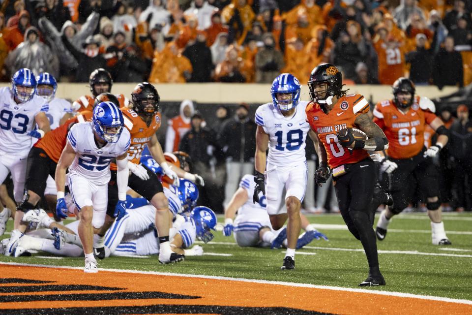 Oklahoma State running back Ollie Gordon II (0) runs past BYU linebacker Ace Kaufusi (18) and safety Talan Alfrey (25) for a touchdown in overtime of an NCAA college football game Saturday, Nov. 25, 2023, in Stillwater, Okla. | Mitch Alcala, Associated Press