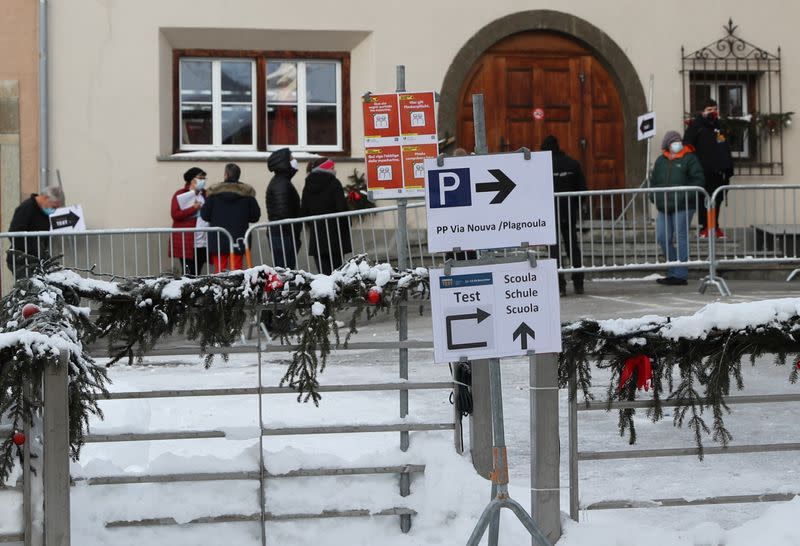 People queue for a COVID-19 test in front of a temporary testing centre in a school in Zuoz