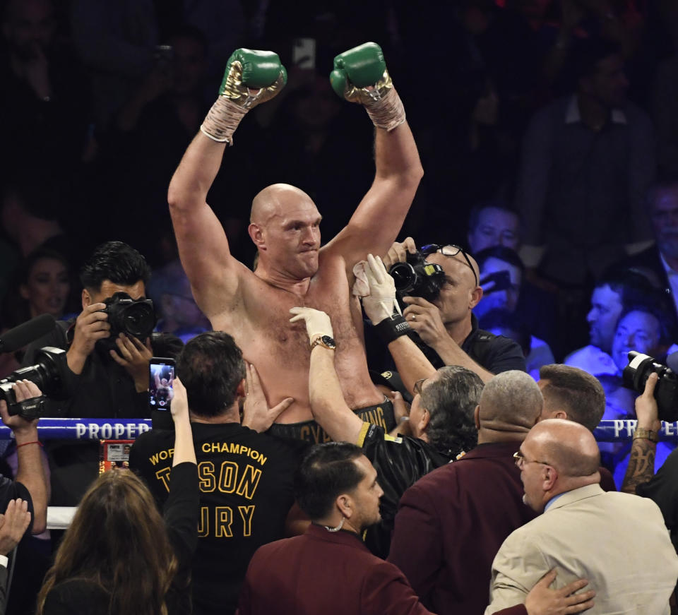 Tyson Fury raises his hands and cheers after going 7 rounds with Deontay Wilder.