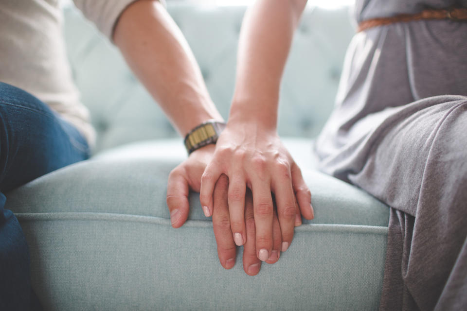 a couple with their hands together on the seat of a couch