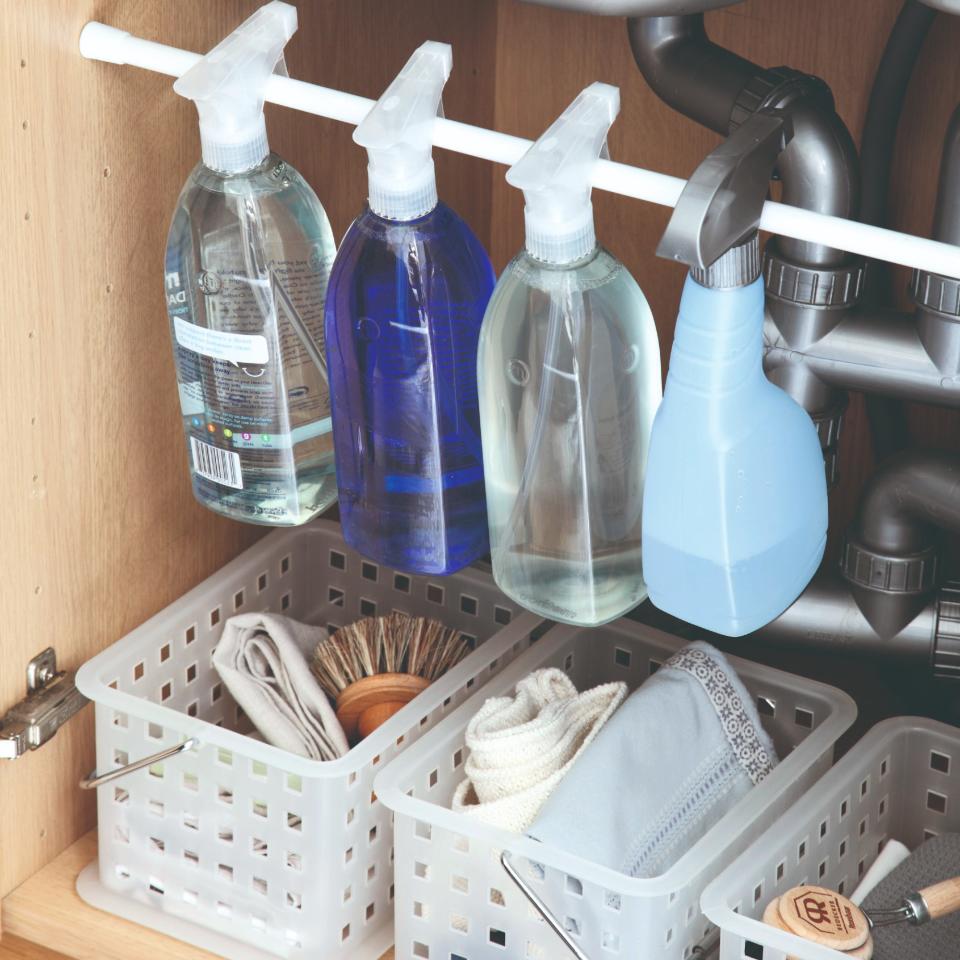  An under-sink cupboard with cleaning products and supplies. 