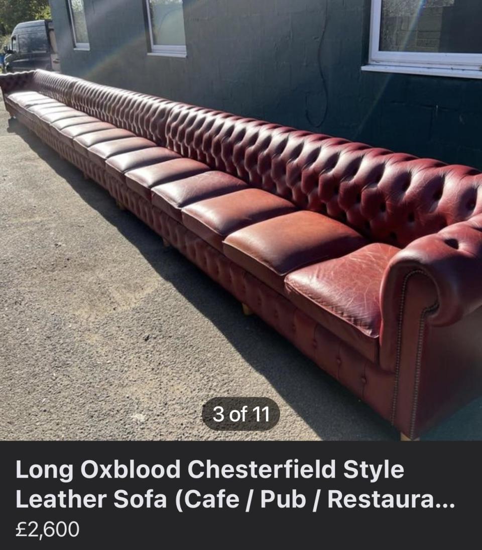 A sofa posted online for sale, and it is extremely long; it sits in a straight line and has seating for 15 people