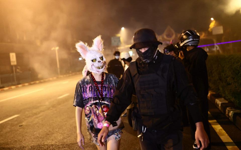 Anti-government protesters, one wearing an animal head as another wears protective gear, walk together after police fire tear gas during a demonstration to mark the 15-year anniversary since the 2006 military takeover in Bangkok on 19 September 2021, as they urge the resignation of the current administration over its handling of the Covid-19 pandemic - Jack Taylor/AFP