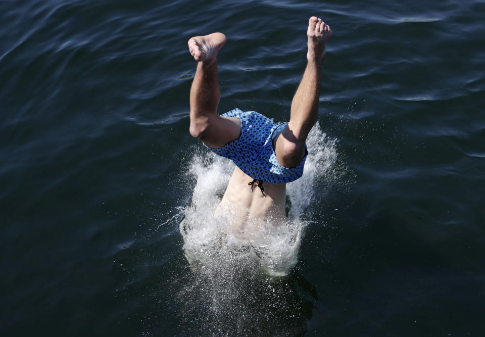 A person dives into the water from a pedestrian bridge at Lake Union Park into the water during a heat wave hitting the Pacific Northwest, Sunday, June 27, 2021, in Seattle. Yesterday set a record high for the day with more record highs expected today and Monday. (AP Photo/John Froschauer)