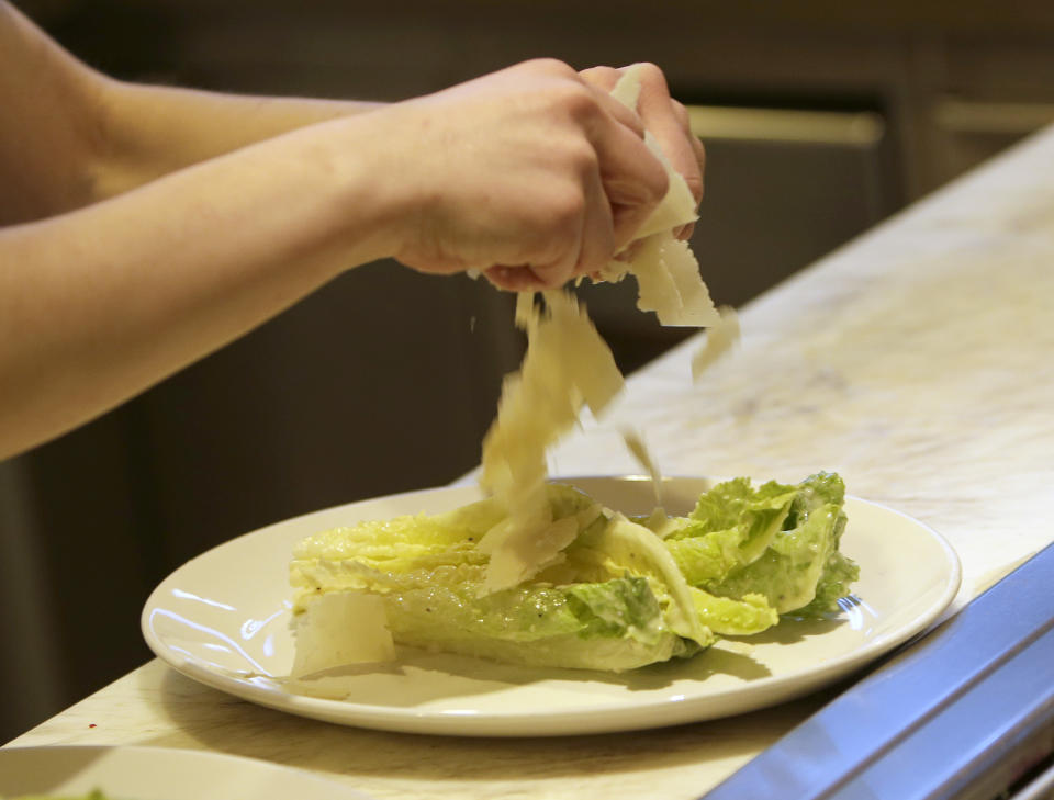 In this photo taken Tuesday,March 11, 2014, pantry cook Alicia Palenyy uses her bare-hands to put cheese on a salad at the Hock Farm restaurant in Sacramento, Calif. Under a bill signed last year by Gov. Jerry Brown, chefs and bartenders in California must keep bare hands off food going straight to the plate or the drink glass, and must use gloves or kitchen utensils such as tongs. California, where the law took effect Jan. 1 and will begin enforcement starting in July, will join 41 other states banning bare-hand contact with ready-to-eat food. In February,after receiving a petition from bartenders calling for an exemption for the "disposable glove law" the law's author, Assemblyman Richard Pan, D-Sacramento, a pediatrician, has introduced a bill to repeal the new regulation and revisit the entire issue.(AP Photo/Rich Pedroncelli)