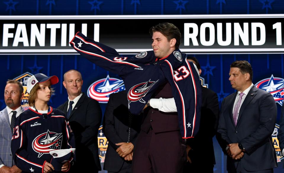 Jun 28, 2023; Nashville, Tennessee, USA; Columbus Blue jackets draft pick Adam Fantilli puts on his sweater after being selected with the third pick in round one of the 2023 NHL Draft at Bridgestone Arena. Mandatory Credit: Christopher Hanewinckel-USA TODAY Sports