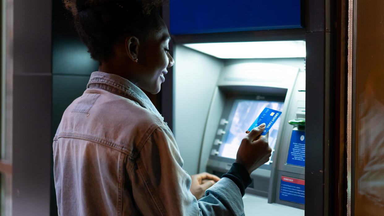 Afro American woman withdrawing money at the ATM.