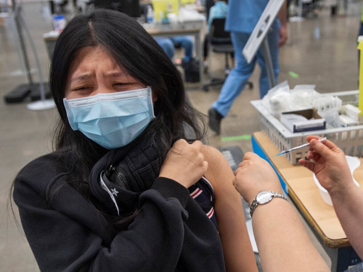 A woman reacts after getting her COVID-19 vaccine last spring. (THE CANADIAN PRESS/Ryan Remiorz - image credit)