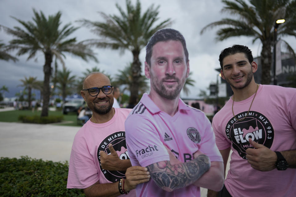 Men hold a cardboard cutout of Inter Miami forward Lionel Messi before gates opened for Inter Miami's Leagues Cup soccer match against Orlando City, Wednesday, Aug. 2, 2023, in Fort Lauderdale, Fla. (AP Photo/Rebecca Blackwell)