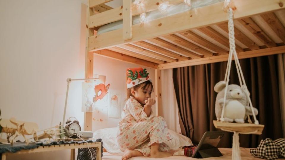 Little girl is watching a cartoon on a digital tablet in her bedroom