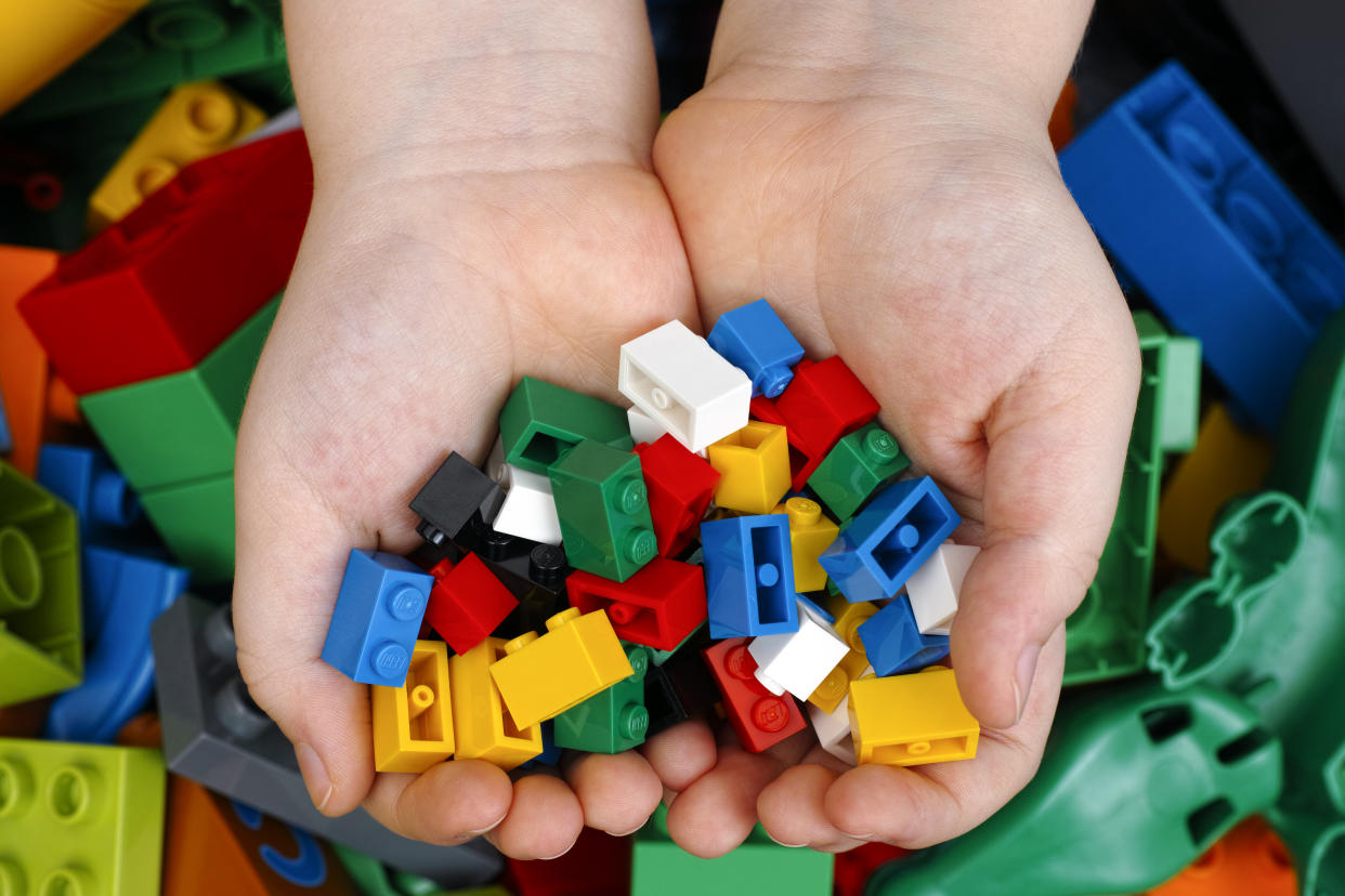 Tambov, Russian Federation - February 20, 2015 Lego Bricks in child's hands with Lego Duplo blocks and toys background. Studio shot.