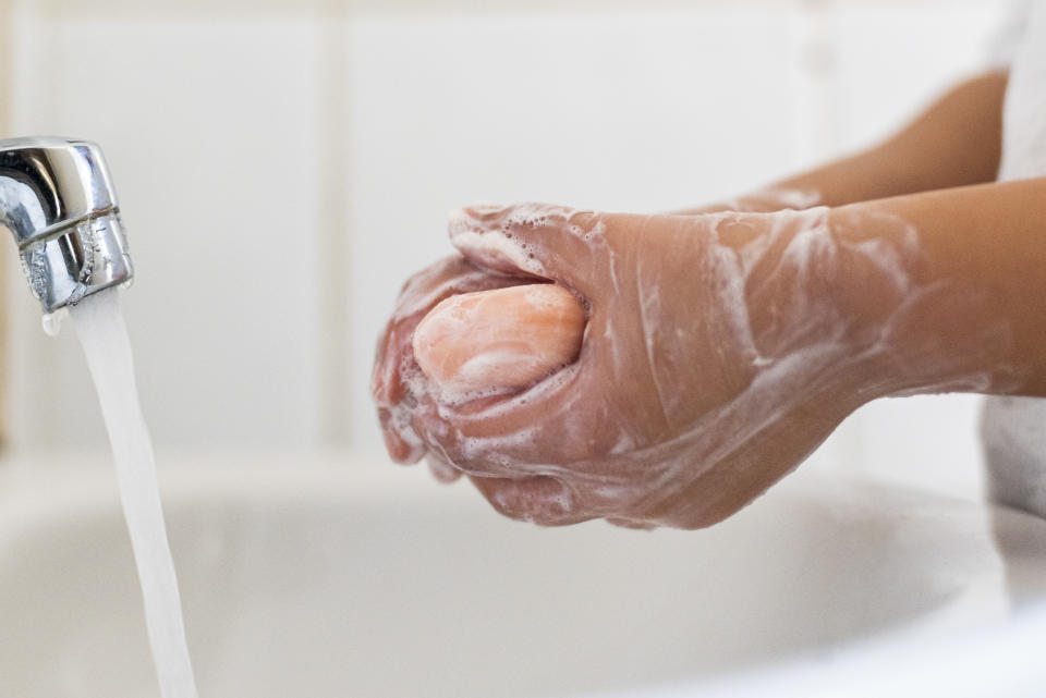 Child, 8-9, is washing her hands with soap in the bathroom.