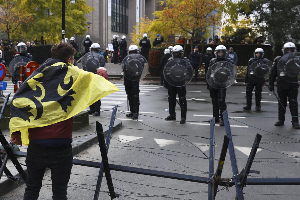 A protestor arguments with riot police officers during a demonstration against the reinforced measures of the Belgium government to counter the latest spike of the coronavirus in Brussels, Belgium, Sunday, Nov. 21, 2021. Many among them also protested against the strong advice to get vaccinated and any moves to impose mandatory shots. (AP Photo/Olivier Matthys)