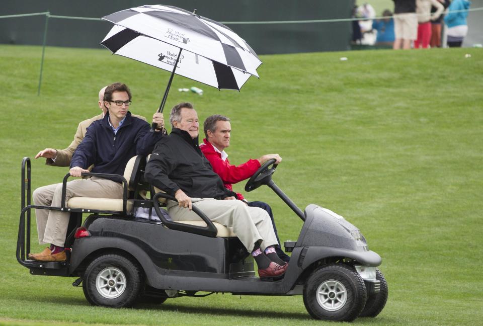 Former President George H.W. Bush rides out onto the 18th green during the final round of the Houston Open golf tournament, Sunday, April 6, 2014, in Humble, Texas. (AP Photo/Patric Schneider)