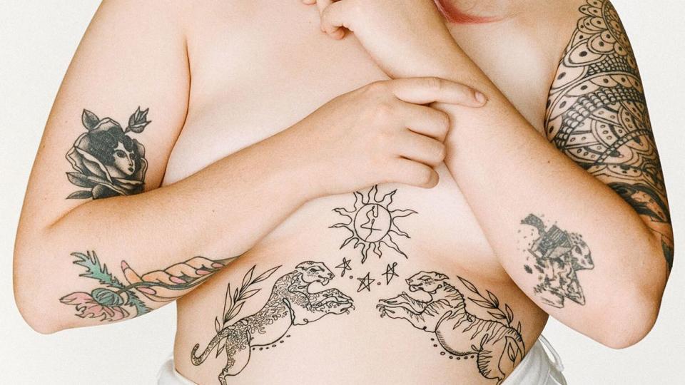 pink-haired woman with stomach tattoo of two cats