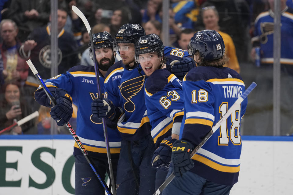 St. Louis Blues' Jake Neighbours (63) is congratulated by teammates Nick Leddy, left, Pavel Buchnevich and Robert Thomas (18) after scoring during the second period of an NHL hockey game against the Calgary Flames Thursday, March 28, 2024, in St. Louis. (AP Photo/Jeff Roberson)