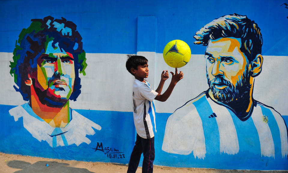 SYLHET, BANGLADESH - DECEMBER 14: A young Argentina fan poses in front of a mural of Lionel Messi, after Argentinas win over Croatia in the semi-final to qualify for the World Cup Final. Bangladesh has never qualified for any football world cup, but has great love for football and has huge fan followings for both Argentina and Brazil. On December 14, 2022 in Sylhet, Bangladesh. (Photo credit should read Md Rafayat Haque Khan/ Eyepix Group/Future Publishing via Getty Images)