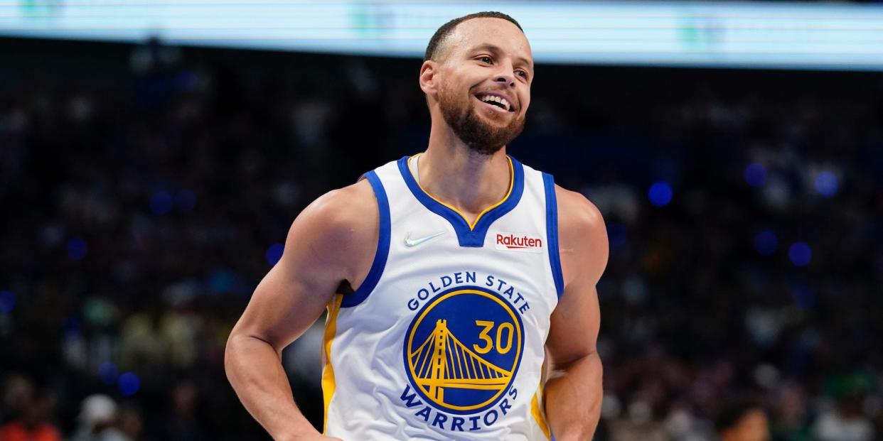 Stephen Curry smiles as he runs on the court.