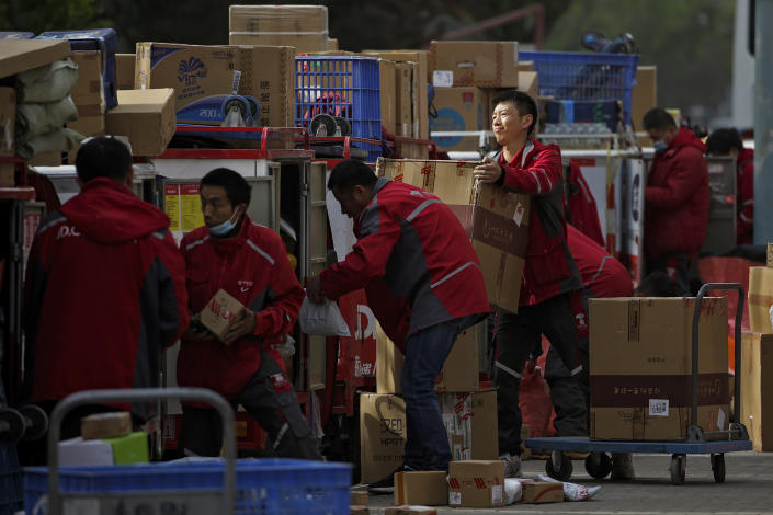 FILE - In this April 27, 2020, file photo, employees of a private delivery company sort out parcels at a distribution center in Beijing. Shortages of power, computer chips and other parts, soaring shipping costs and shutdowns of factories to battle the pandemic are taking a toll on Asian economies. (AP Photo/Andy Wong, File)