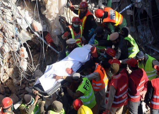 Pakistani rescue workers remove the body of a woman from the debris of a collapsed building in Lahore on Tuesday, as the death toll rises to 19