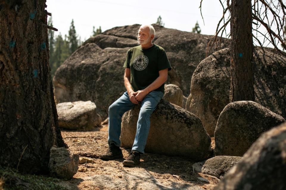 Michael Hicks sits outside on a large rock