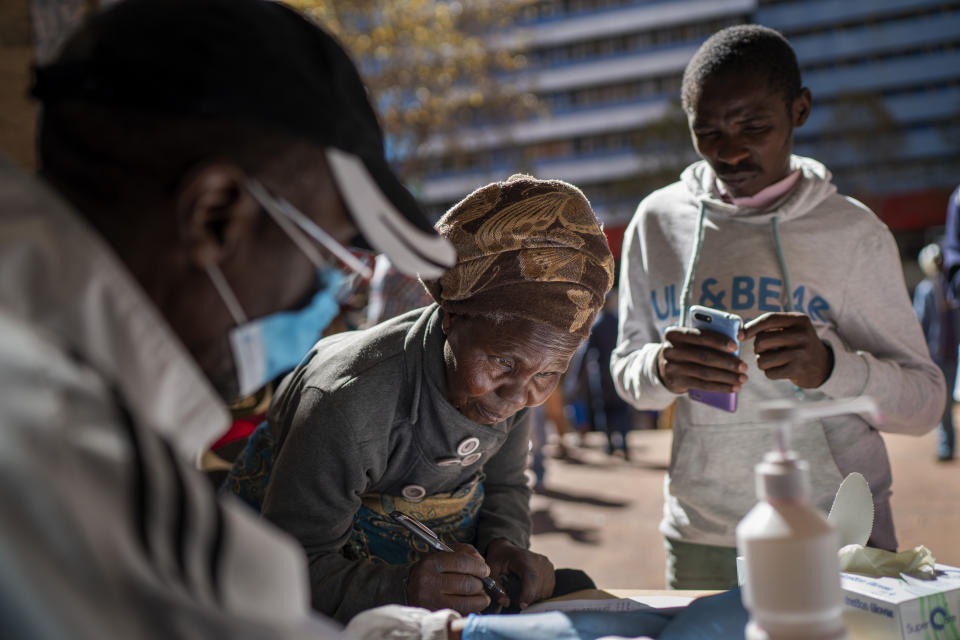 An informal vendor fills out paperwork to be granted a temporary working license, at the entrance of a municipal office building, in Johannesburg, Tuesday, April 7, 2020. South Africa and more than half of Africa's 54 countries have imposed lockdowns, curfews, travel bans or other restrictions to try to contain the spread of COVID-19. (AP Photo/Jerome Delay)