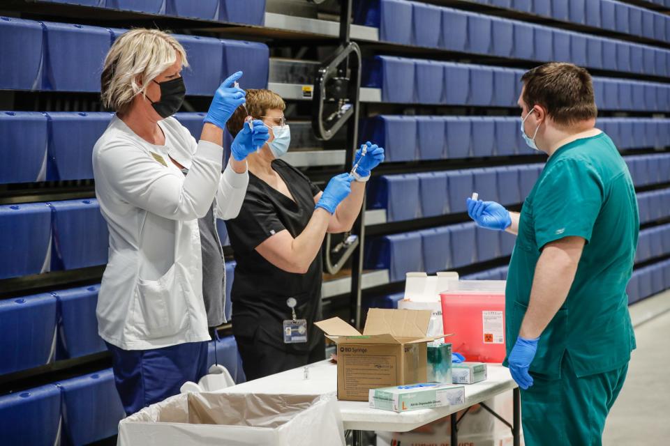 From the left, Marie Beechy MSN, RN, Assistant Professor Leighton School of Nursing, faculty member Lyree Mikhail, and faculty member Brian Skinner prepare the Pfizer COVID-19 Vaccine for the Marian University vaccine clinic, held on Wednesday, April 28, 2021, in the Marian University Arena in Indianapolis. 